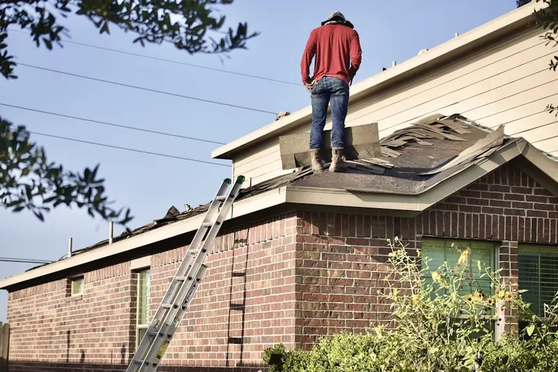 Professional roofer working on a residential roof in Dent